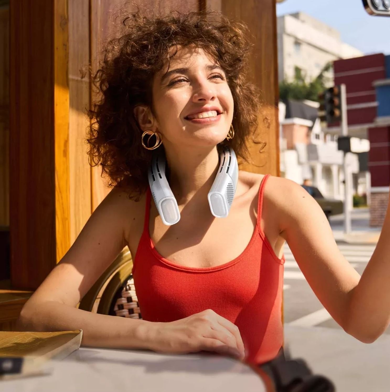 person at an outdoor cafe wearing Coolify 2 wearable neck fan with cooling and heating functions outdoors